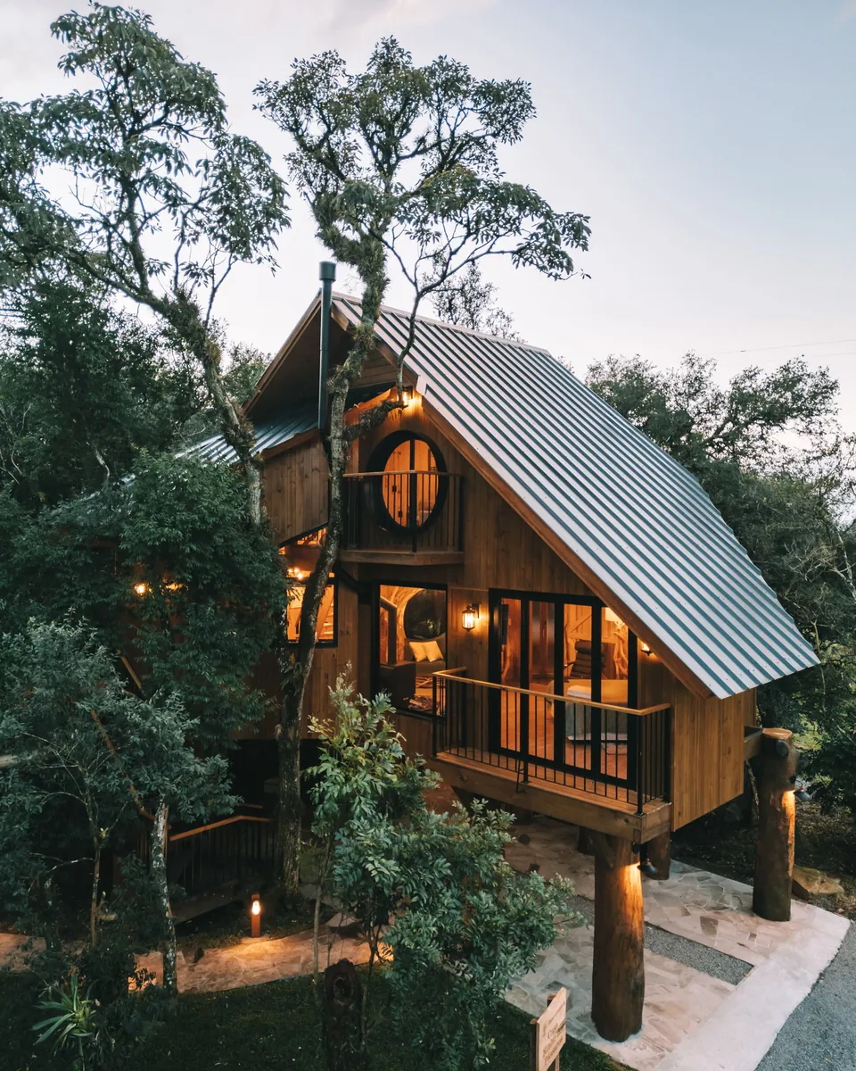 A casa na árvore Ninho dos Pássaros ao entardecer, com as luzes acesas