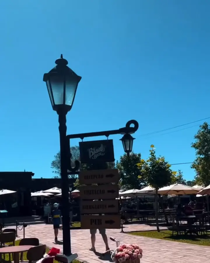 O poste com a placa da Blauth Bier Cervejaria e o bier garten ao fundo